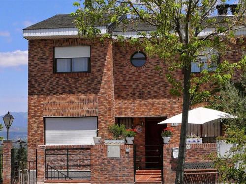 a brick house with an umbrella in front of it at Belvilla by OYO Casa Alegr a in Galapagar
