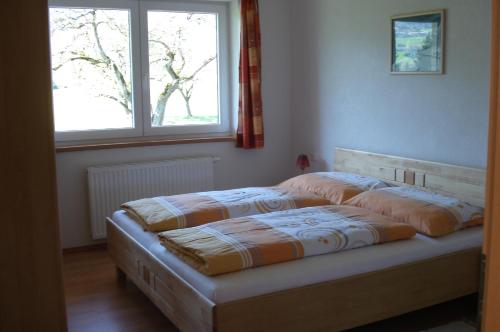 ein Bett in einem Schlafzimmer mit einem Fenster in der Unterkunft Ferienwohnungen Simon - Hauserhof in Oberperfuss