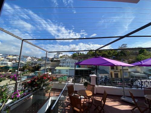 a balcony with tables and chairs and purple umbrellas at Marguerite Villa in Da Lat