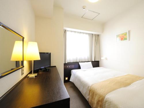a hotel room with a bed and a television at Hotel S-plus Nagoya Sakae in Nagoya