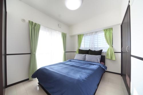 - une chambre avec un lit bleu et des rideaux verts dans l'établissement EX Itoman Apartment 503, à Teruya
