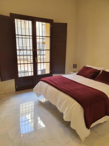 a bedroom with a large bed and a large window at Habitaciones Casa Sevillana Centro in Seville