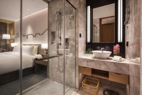 uma casa de banho com um chuveiro, uma cama e um lavatório. em Holiday Inn Nanjing Qinhuai South, an IHG Hotel em Jiangning