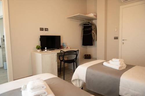 a room with two beds and a desk with a television at Bed and breakfast Ma.Gi.A in Cuneo
