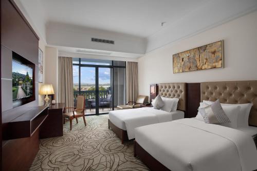 a hotel room with two beds and a television at Wyndham Garden Haikou South in Haikou