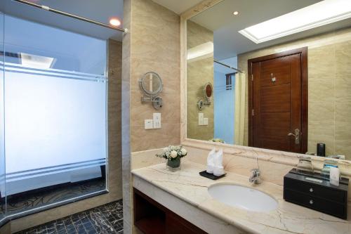 a bathroom with a sink and a large mirror at Wyndham Garden Haikou South in Haikou