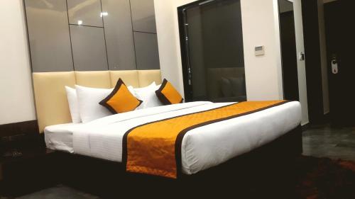 齋浦爾的住宿－Hotel Aksh Inn，一间卧室配有一张带橙色和白色枕头的大床