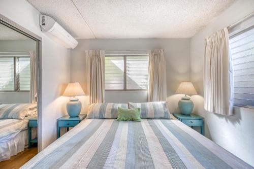 a bedroom with a bed and two blue tables at Kihei Kai Nani in Kihei