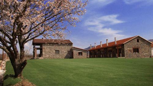 a large stone building with a large grass field at Ihnilatis in Kerkíni