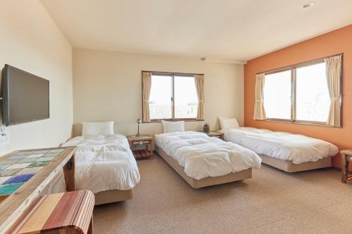 a bedroom with two beds and a flat screen tv at HOTEL tuka miika in Ishigaki Island