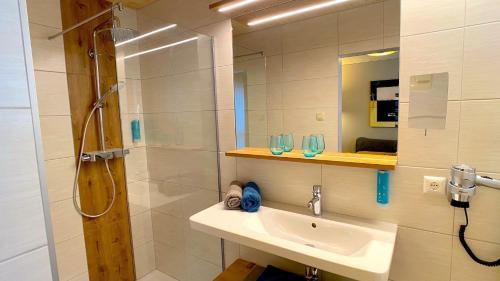 a bathroom with a sink and a shower and a mirror at Himmelsbögen und Apartments mit Seeblick und Alleinlage in Weissensee