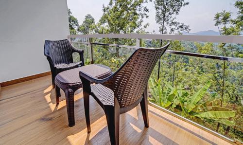 two chairs on a balcony with a view of trees at Treebo Wanderlust Residency With Mountain View in Munnar
