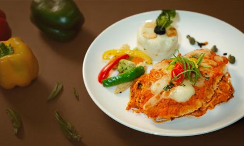 a white plate of food with vegetables on a table at Hotel Vdara in Vijayawāda