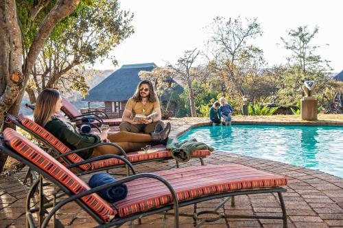 two women sitting on chairs next to a swimming pool at Valamanzi Lodge in Nyati Wilderness in Vaalwater