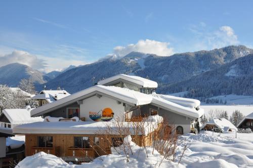 a house covered in snow with mountains in the background at Himmelsbögen und Apartments mit Seeblick und Alleinlage in Weissensee