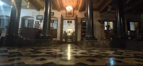 a hallway of a building with columns and a clock at Chettinadu Mansion – An Authentic Heritage Palace in Kānādukāttān