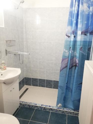 a bathroom with a shower with a blue shower curtain at szt.flórián in Cserszegtomaj