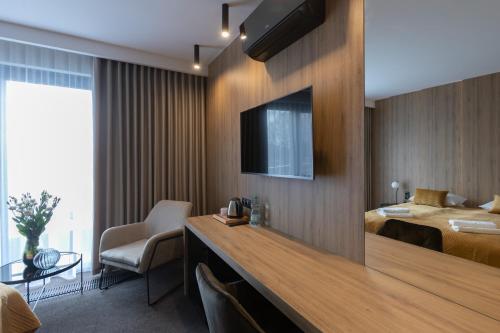 a hotel room with a bed and a television on a wall at Apartamenty Green Place in Kańczuga