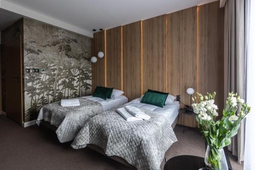 a bedroom with two beds and a vase of flowers at Apartamenty Green Place in Kańczuga