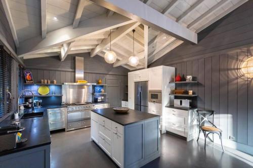 une grande cuisine avec des placards blancs et un comptoir noir dans l'établissement La Villa du Phare - 240 m² avec 5 chambres piscine, à Lège-Cap-Ferret