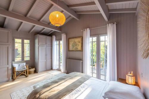 una camera con un grande letto in una stanza con finestre di La Villa du Phare - 240 m² avec 5 chambres piscine a Lège-Cap-Ferret