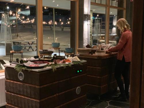 a woman standing in front of a counter with food at Mountain Lodge in Stöten