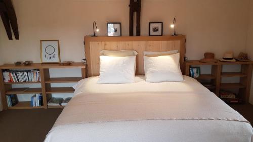 1 dormitorio con 1 cama con sábanas y almohadas blancas en Les Peyronnies, en Figeac