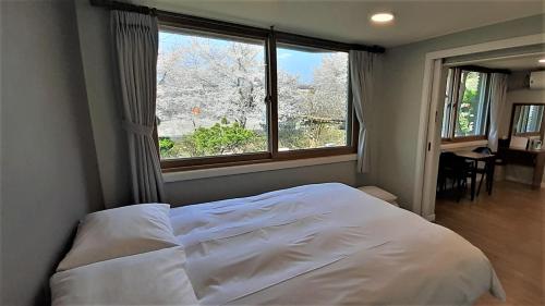a bedroom with a white bed and a large window at Hotel Jirisan Haetsal in Gurye