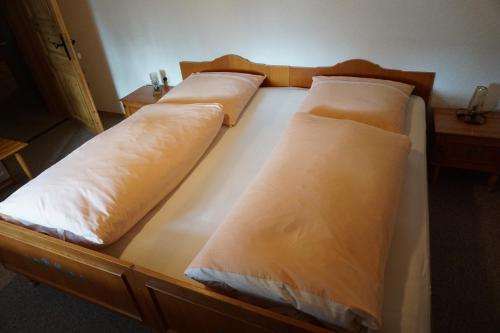 a bed with four pillows on it in a room at Pension & Fewos Fuchs in Mauth