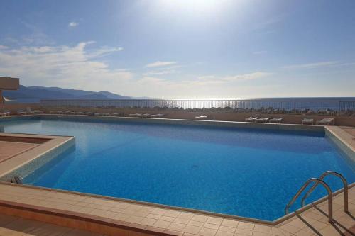 una gran piscina azul con vistas al océano en FACE MER ENTRE PLAGE ET MARINA, en Bormes-les-Mimosas