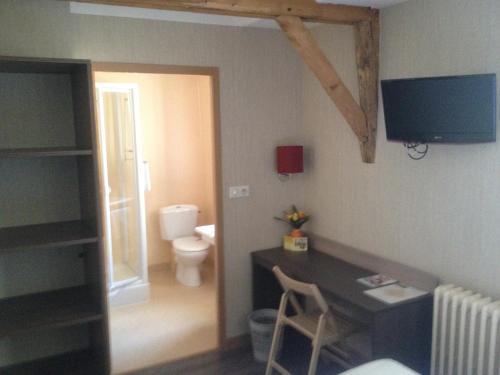 um quarto com uma secretária, um WC e uma televisão em Hotel du Commerce em Cholet