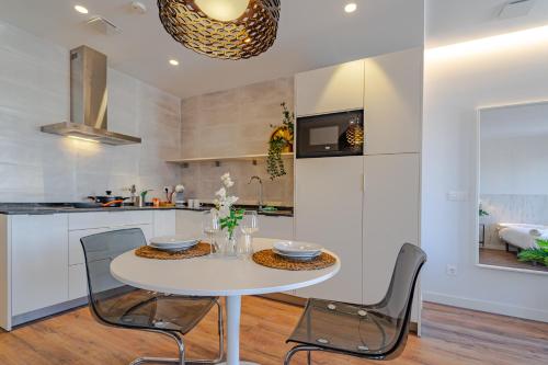 a white kitchen with a white table and chairs at Edificio 13 by Plaza Mayor Apartamentos in Valladolid