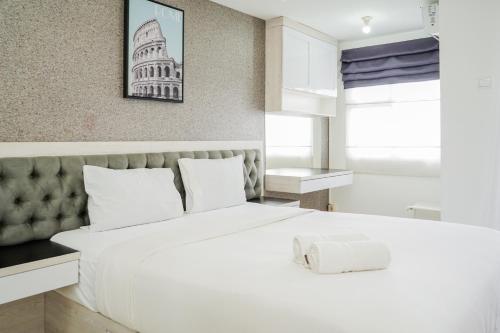 a bedroom with a large white bed with a wall at Remarkable Studio at Baileys City Apartment By Travelio in Pondokcabe Hilir