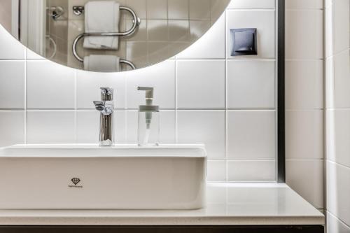La salle de bains est pourvue d'un lavabo et d'un miroir. dans l'établissement Part-Time Home Täby, à Täby