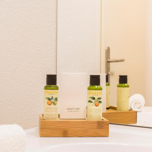 two bottles of orange essential oils sitting on a bathroom sink at Zenao Appart'hôtels Villeneuve-lès-Avignon in Villeneuve-lès-Avignon