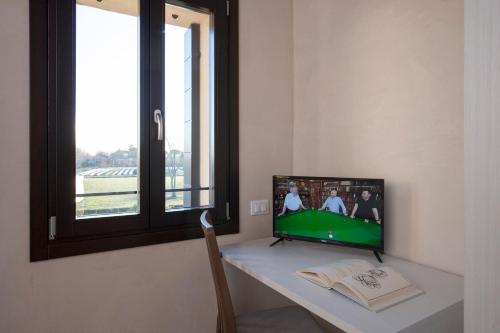 a room with a desk with a television and a window at Casa Di Anna - Fattoria Sociale in Mestre