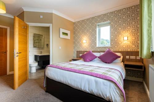 a bedroom with a bed with purple pillows and a bathroom at White House in St Asaph