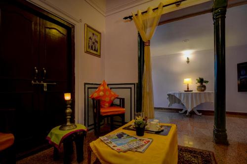 a living room with a table with a yellow table cloth at The Umaid Vilas Royal Heritage Haveli in Jaipur