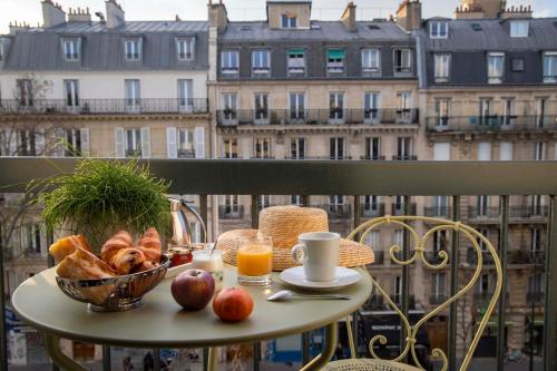une table avec un panier de pain et de fruits sur un balcon dans l'établissement Hôtel Des Mines, à Paris