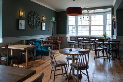 a restaurant with tables and chairs and a clock on the wall at Coach House Inn in Dorchester
