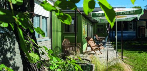 eine Person, die auf der Veranda eines grünen Hauses sitzt in der Unterkunft Le Riolet in Marsac-en-Livradois
