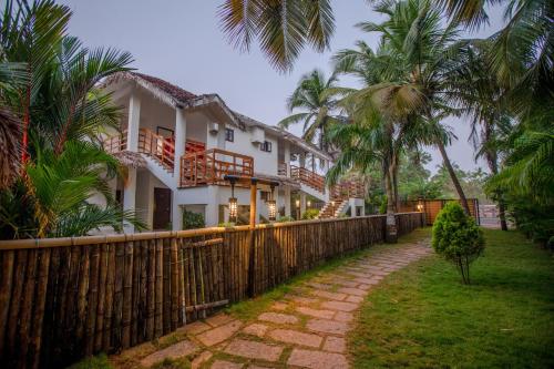 a white house with a fence and palm trees at Malabar Ocean Front Resort And Spa, Bekal in Nīleshwar