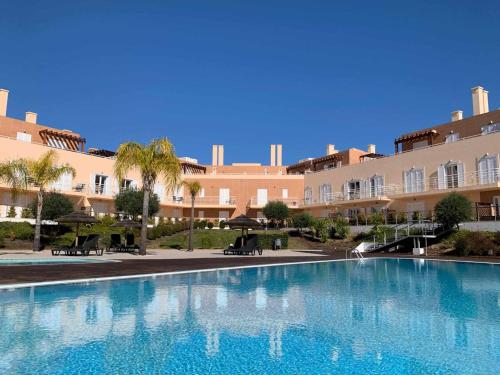 a large swimming pool in front of a large building at Apartamento VerdeMar Cabanas Gardens by Your Home Algarve in Cabanas de Tavira