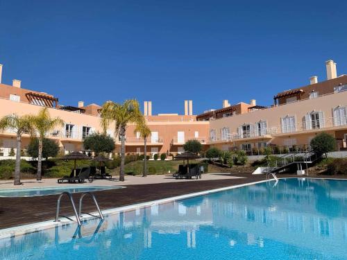 une grande piscine en face d'un grand bâtiment dans l'établissement Apartamento VerdeMar Cabanas Gardens by Your Home Algarve, à Cabanas de Tavira