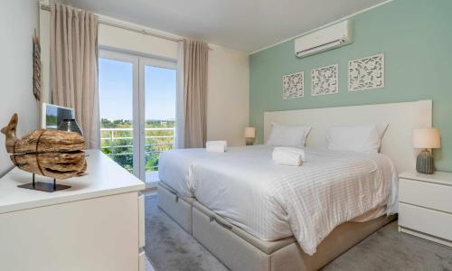 a bedroom with a white bed and a window at Apartamento VerdeMar Cabanas Gardens by Your Home Algarve in Cabanas de Tavira