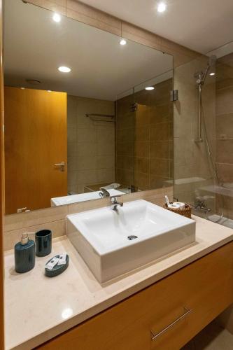 a bathroom with a sink and a large mirror at Apartamento VerdeMar Cabanas Gardens by Your Home Algarve in Cabanas de Tavira