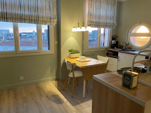 a kitchen with a table and chairs and two windows at Vue sur rade appartement élégant vaste climatisé étage élevé ascenseur proche parking et toutes commodités au cœur du Toulon historique in Toulon