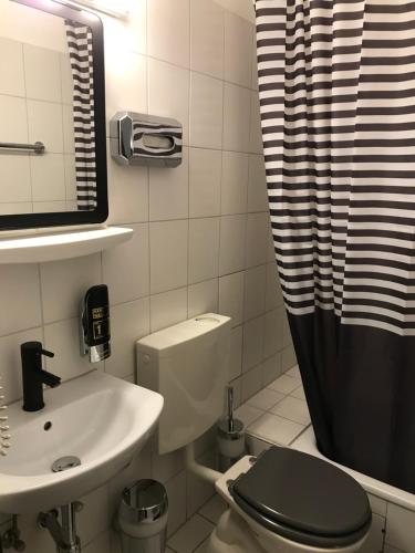 a bathroom with a toilet and a sink and a shower at Hotel Ko in Düsseldorf