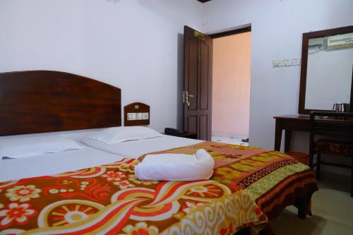 a bedroom with a bed with a red and yellow blanket at Ramanilayam Tourist Home in Ambalapulai