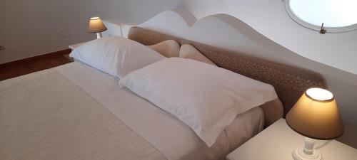 een slaapkamer met een bed met witte kussens en 2 lampen bij La casa del Capitano B&b in Positano